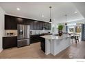 Modern kitchen featuring dark cabinetry, stainless steel appliances, and a spacious white countertop island at 542 Highlands Cir, Erie, CO 80516