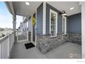 Charming covered porch with stone accents and a welcoming yellow floral wreath on the front door at 542 Highlands Cir, Erie, CO 80516