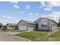Street view of a cozy single-story house featuring an attached two-car garage and green front lawn at 6150 Bluestem Grn, Frederick, CO 80530
