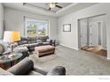 Spacious living room featuring plush carpeting, a ceiling fan, and an expansive view from the large window at 6150 Bluestem Grn, Frederick, CO 80530