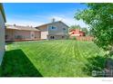 Expansive backyard featuring a lush lawn perfect for outdoor activities, back deck, and mature trees at 8963 W 75Th Cir, Arvada, CO 80005