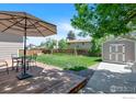 Inviting backyard with a wooden deck, outdoor seating, lush lawn, storage shed, and mature landscaping at 8963 W 75Th Cir, Arvada, CO 80005