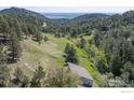 Scenic aerial view of a wooded valley with a home's rooftop visible, showcasing the property's natural surroundings at 100 Wildcat Ln, Boulder, CO 80304