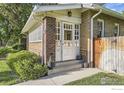 Close up of a quaint brick home featuring a charming white-framed front door and well-kept landscaping at 1230 S Emerson St, Denver, CO 80210