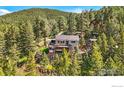 Hillside home with a large deck, hot tub, and green space surrounded by mature trees at 141 Millionaire W Dr, Boulder, CO 80302