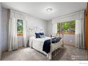 Cozy bedroom featuring patterned wallpaper, neutral carpet, and windows framing peaceful outdoor views at 1528 16Th Pl, Longmont, CO 80501