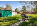 Fenced yard with green shed, white shed and bbq smoker on a concrete path at 1542 Kilkenny St, Boulder, CO 80303