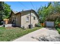 View of a house with a detached garage, set amidst green lawn and mature trees at 2200 Teller St, Lakewood, CO 80214