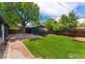 Private backyard with a large shed, mature tree, lush grass, and brick patio at 2749 S Glencoe St, Denver, CO 80222