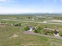 Aerial view of a charming home with a spacious lot, and an airfield in the background at 2875 Mooney Pl, Erie, CO 80516