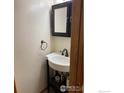 Compact powder room with a pedestal sink, sleek black fixtures, and a modern vanity mirror at 2929 W 81St Ave # H, Westminster, CO 80031