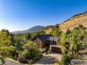 Aerial view of a modern home with a wood and stone exterior, nestled among lush greenery with mountain views at 3737 Spring Valley Rd, Boulder, CO 80304