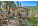 Charming mountain cabin with metal siding, a welcoming deck, and serene forest surroundings at 398 Fred Rd, Boulder, CO 80302