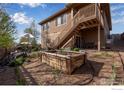 Landscaped backyard featuring a raised garden bed and outdoor seating area with stairs to deck at 4000 Donnington Cir, Castle Rock, CO 80104