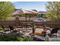 Backyard patio with table, chairs, a patio umbrella, and play set, surrounded by lush greenery at 4000 Donnington Cir, Castle Rock, CO 80104
