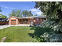 Charming brick home featuring an inviting front porch and well-manicured lawn at 1234 S Holland Ct, Lakewood, CO 80232