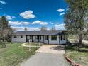 Charming ranch-style house featuring a covered front porch, a well-manicured lawn, and a circular driveway at 1428 S County Road 23E, Berthoud, CO 80513