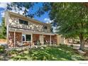 Inviting two-story brick home featuring a cozy front porch with seating and a well-manicured lawn at 1513 Elmhurst Dr, Longmont, CO 80503