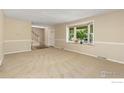 Bright living room featuring a bay window, neutral tones, and carpet flooring at 1513 Elmhurst Dr, Longmont, CO 80503