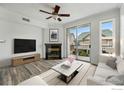 Bright living room with wood floors, fireplace, TV, ceiling fan and balcony with a view of the community at 1837 Spaulding Cir, Superior, CO 80027