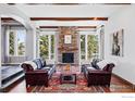Cozy living room featuring a stone fireplace, wood beams, hardwood floors, and large windows with natural light at 290 Skyhill Dr, Evergreen, CO 80439