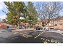 Exterior view of reserved parking lot spots and residential building beyond lush green trees at 316 Wright St # 203, Lakewood, CO 80228