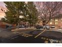 Exterior view of reserved parking lot spots and residential building beyond lush green trees at 316 Wright St # 203, Lakewood, CO 80228