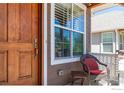 Close up of a wood front door and cozy seating on the front porch at 3341 Yukon Ct, Wheat Ridge, CO 80033