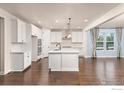 Bright open kitchen features a large center island, white cabinets, hardwood floors, and stainless steel appliances at 4631 Lakeside Dr, Firestone, CO 80504