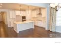 Open kitchen with white cabinets, a central island, and hardwood floors at 4631 Lakeside Dr, Firestone, CO 80504