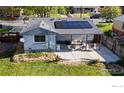 Backyard aerial view featuring a covered patio, a concrete patio, solar panels, and a well-manicured lawn at 6260 W 61St Ave, Arvada, CO 80003