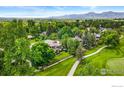 Aerial view of the home and lush green yard with mature trees with mountain views in the background at 7205 Rustic Trl, Boulder, CO 80301