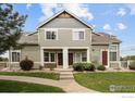 Two-story townhome showcasing a well-manicured front yard and covered entryway with columns at 805 Summer Hawk Dr # 100, Longmont, CO 80504