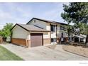Inviting two-story house with a spacious driveway and attached garage, complemented by mature trees and landscaping at 8125 Downing St, Denver, CO 80229