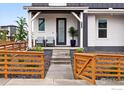 Inviting front porch with stylish seating, a well-manicured yard, and a charming wooden fence for added curb appeal at 926 Hearteye Trl, Lafayette, CO 80026