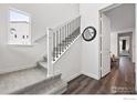 Elegant staircase with carpeted steps, a black iron railing, and ample natural light from a nearby window at 926 Hearteye Trl, Lafayette, CO 80026