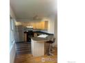 Well-lit kitchen features stainless steel appliances, light wood cabinets, breakfast bar, and hardwood flooring at 936 Parkview St, Louisville, CO 80027