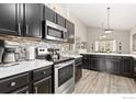 Modern kitchen with stainless steel appliances, dark cabinetry, and light countertops at 9930 Cascade St, Firestone, CO 80504