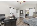 Bright home office featuring vaulted ceilings, hardwood floors, and sliding barn doors at 9930 Cascade St, Firestone, CO 80504