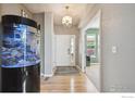 Inviting entryway featuring wood floors, chandelier, fish tank, and seamless transition to home office at 14049 Detroit Dr, Thornton, CO 80602