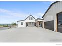 Eye-catching farmhouse with white siding, black trim, and a generous concrete driveway at 14407 County Road 18 1/2 Rd, Fort Lupton, CO 80621
