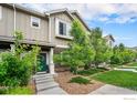 Charming townhome featuring well-kept landscaping, a vibrant green door, and a welcoming entrance at 14700 E 104Th Ave, Commerce City, CO 80022