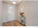 Entryway featuring wood floors, a white front door, and a decorative table at 2200 Cadman St, Berthoud, CO 80513