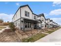 Charming exterior view of townhomes with modern farmhouse design, featuring a covered porch and well-kept landscaping at 3580 W 62Nd Pl, Denver, CO 80221