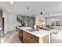 The kitchen island features a white countertop and wooden cabinets, and it's open to the living and dining areas at 3580 W 62Nd Pl, Denver, CO 80221