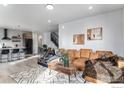 Spacious living room with stylish decor, a comfortable brown leather sofa, and an adjacent dining area and kitchen at 3580 W 62Nd Pl, Denver, CO 80221