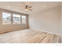 Bright bedroom with large windows, hardwood floors, and a modern ceiling fan at 793 Griffith St, Lochbuie, CO 80603