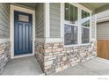 Close-up of a stylish front entrance featuring a blue door, stone accents, and large windows at 793 Griffith St, Lochbuie, CO 80603