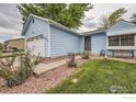 Charming light blue single-story home with a well-maintained front yard, attached garage, and beautiful landscaping at 7951 S Estes St, Littleton, CO 80128