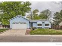 Charming light blue single-story home with a well-maintained front yard, attached garage, and beautiful landscaping at 7951 S Estes St, Littleton, CO 80128